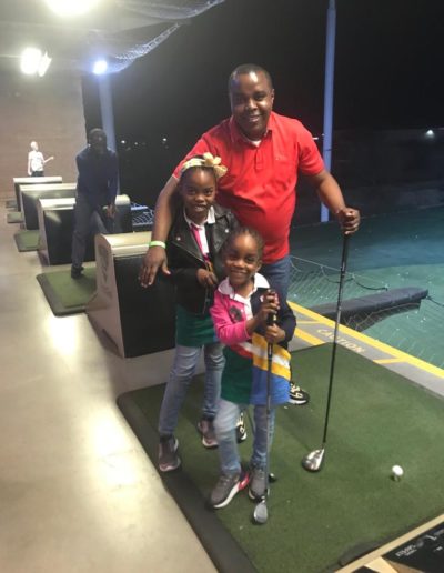 A man with two girls playing golf