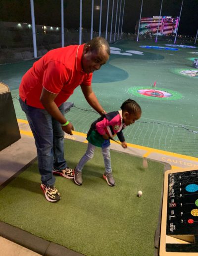 A man teaching a girl to play golf