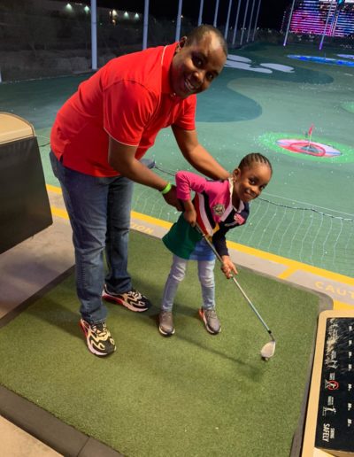 A man helping a girl use a golf club correctly