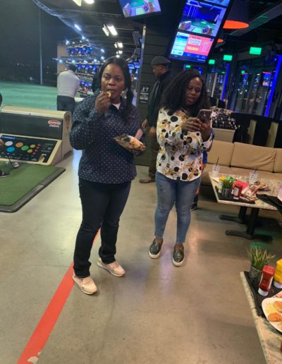 A woman eating chips next to a woman using a phone