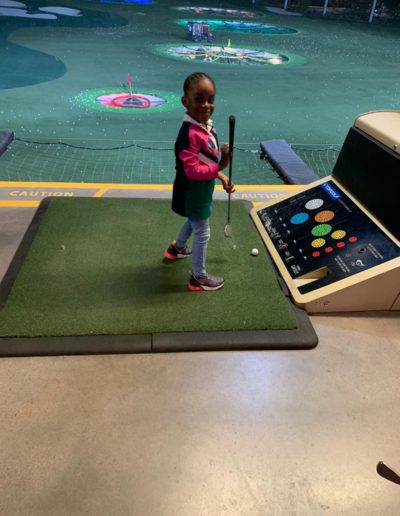 A girl smiling while holding a golf club