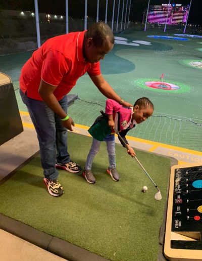 A man helping a girl play golf