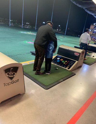 A man helping a boy with his arm movements when playing golf