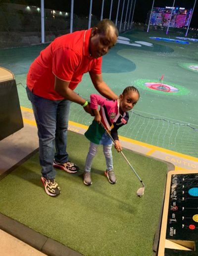 A man helping a girl with swinging a golf club