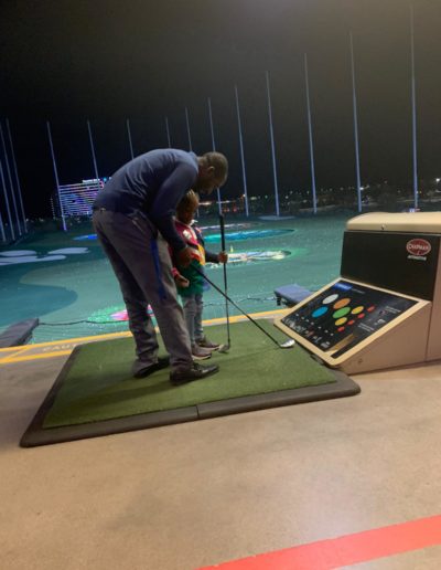 A man teaching a girl how to place a golf club