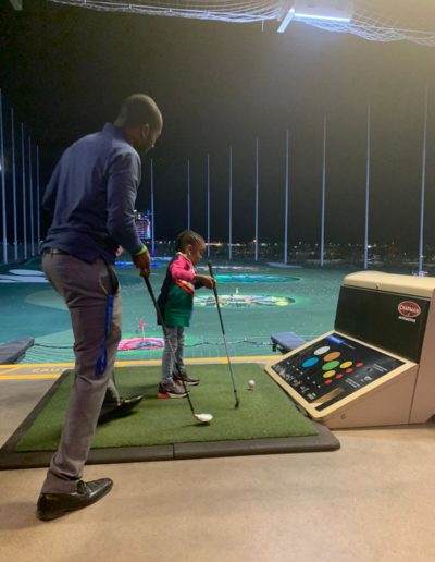 A man moving in to help the girl play golf