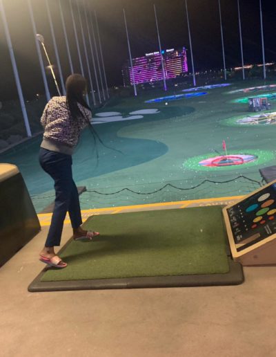 A woman watching the ball after swinging with her golf club