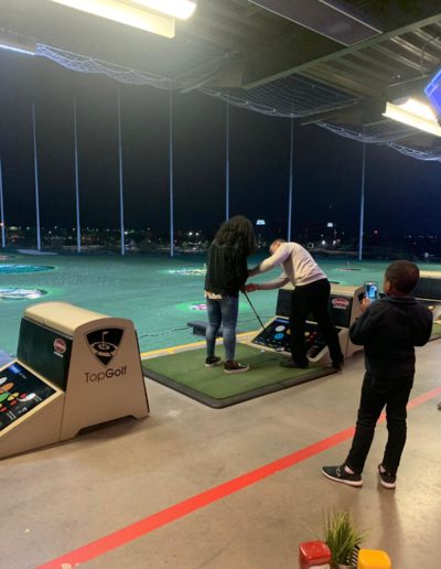 A man teaching a woman how to use a golf club