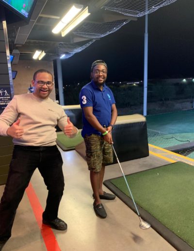 A man showing approval next to a man holding a golf club