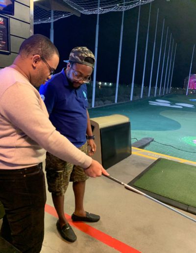 A man teaching a friend how to use a golf club